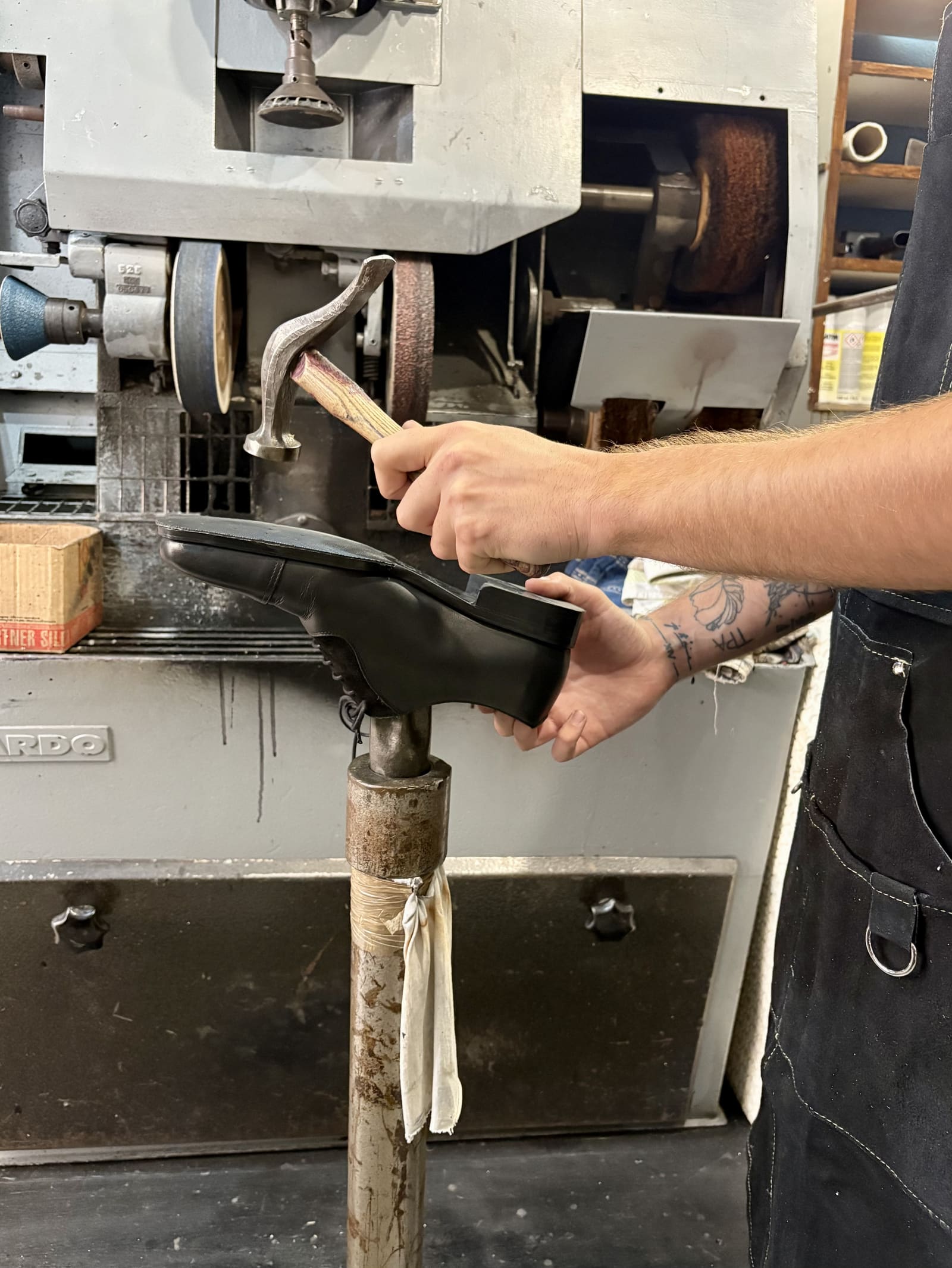 Artisan façonnant une semelle de chaussure au marteau sur un pied en atelier